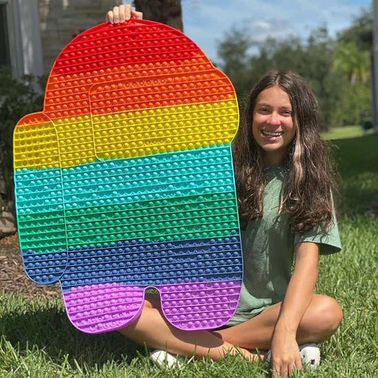 Girl sitting on grass holding Biggest Pop It Fidget Toys kibtoy Girl sitting on grass holding Biggest Pop It Fidget Toys kibtoy